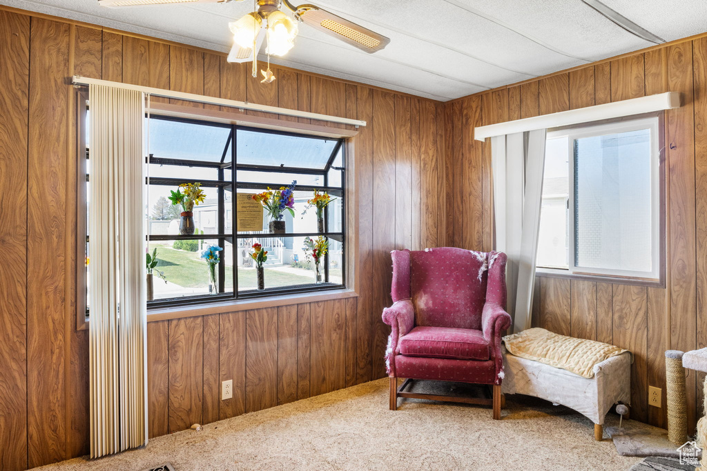 Sitting room featuring wood walls, carpet floors, and a ceiling fan