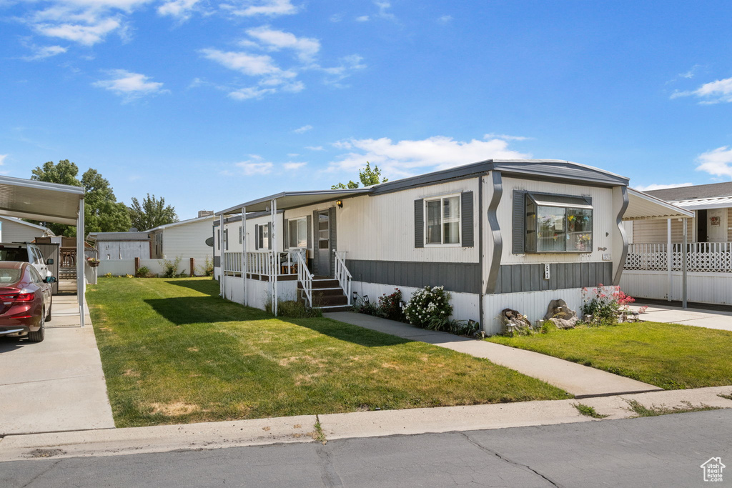 Manufactured / mobile home with a front yard and a carport