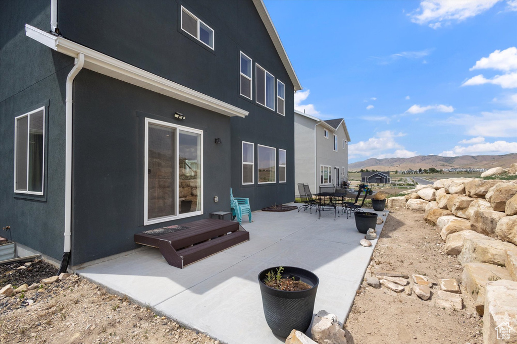 Back of house featuring a mountain view, a patio area, and stucco siding