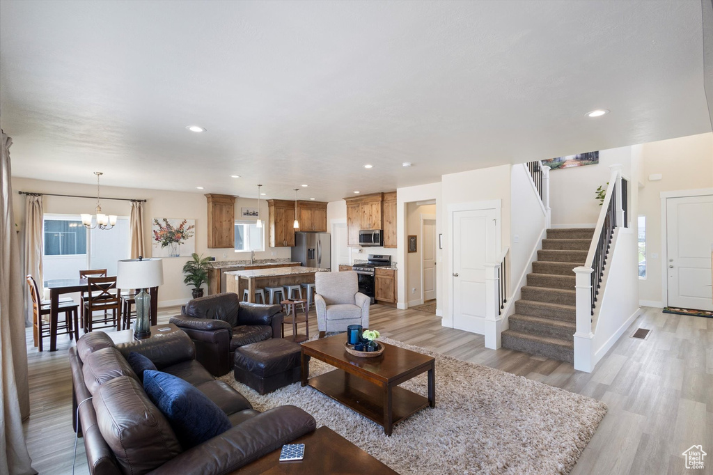 Living area featuring light wood-type flooring, stairway, a chandelier, and recessed lighting