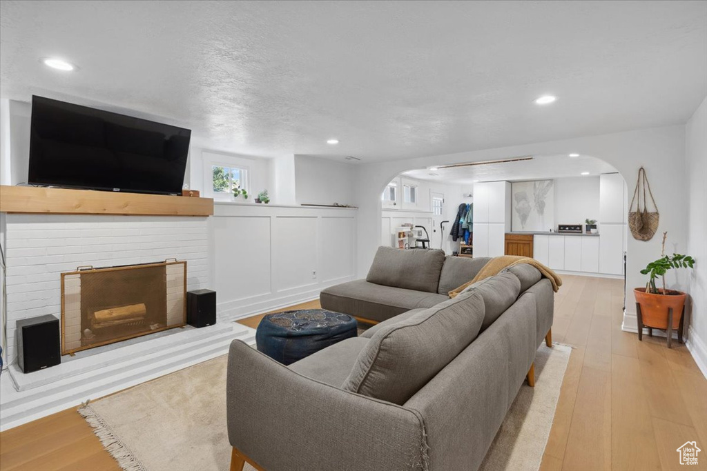 Living room with arched walkways, a fireplace, wood finished floors, and recessed lighting