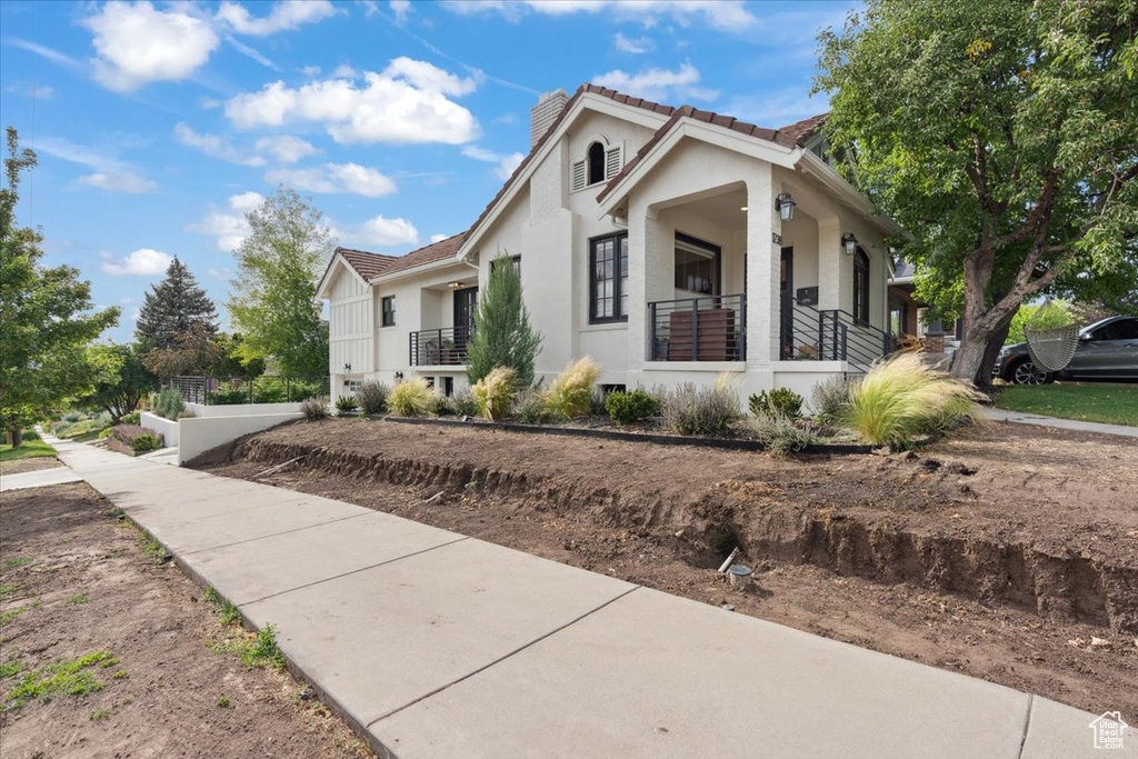 View of front of house featuring stucco siding, a chimney, and a tiled roof