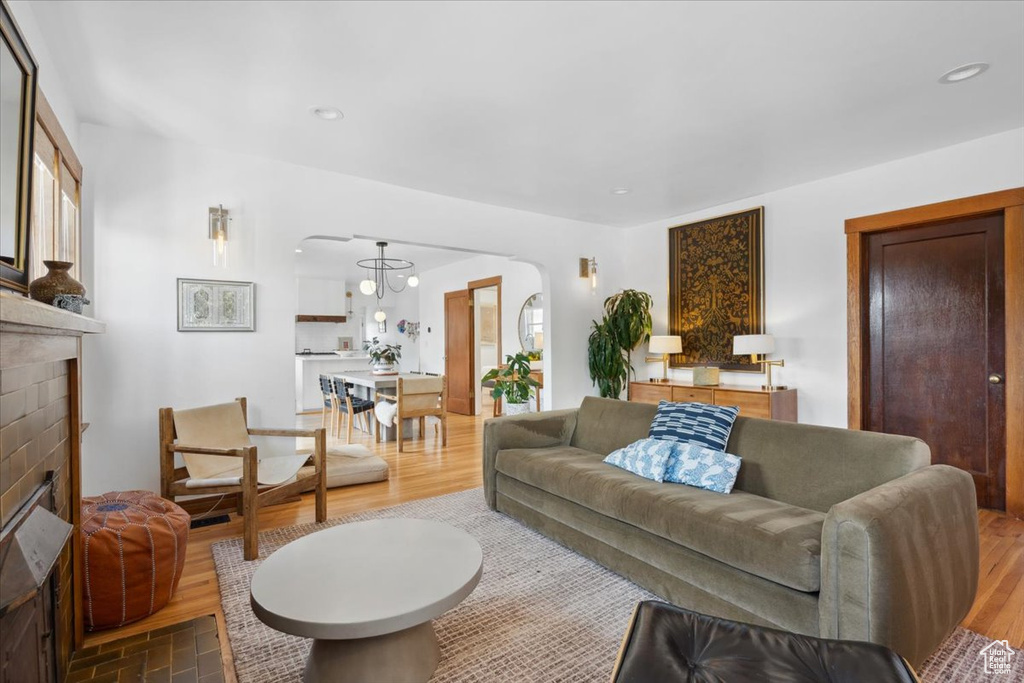 Living area featuring wood finished floors, a glass covered fireplace, arched walkways, and recessed lighting