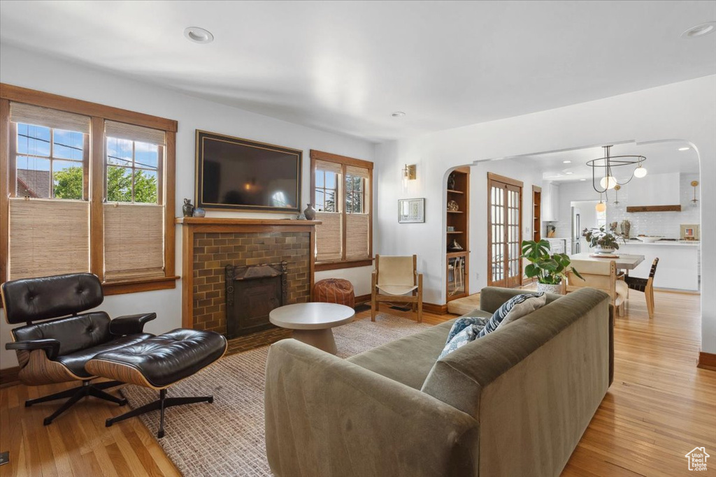 Living area featuring arched walkways, light wood-style flooring, a fireplace, plenty of natural light, and recessed lighting