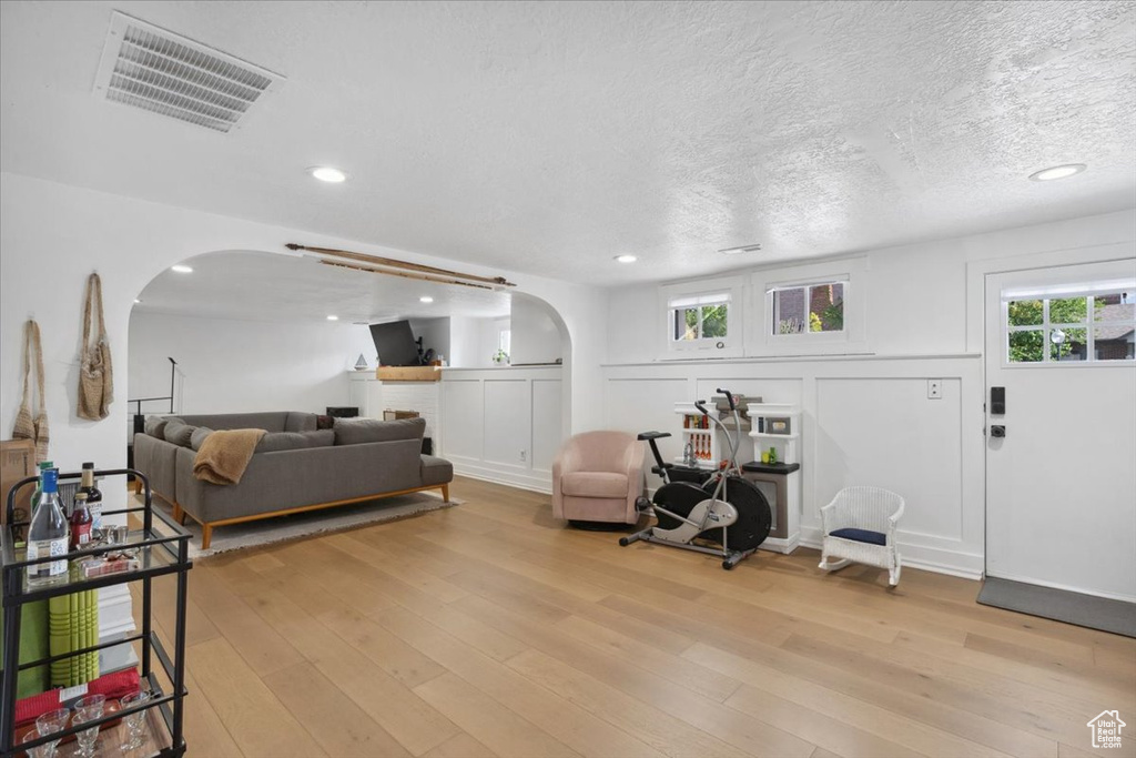 Living area with arched walkways, light wood-style floors, recessed lighting, and a textured ceiling