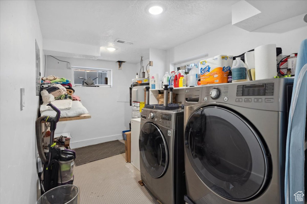 Laundry room featuring separate washer and dryer, a textured ceiling, and water heater
