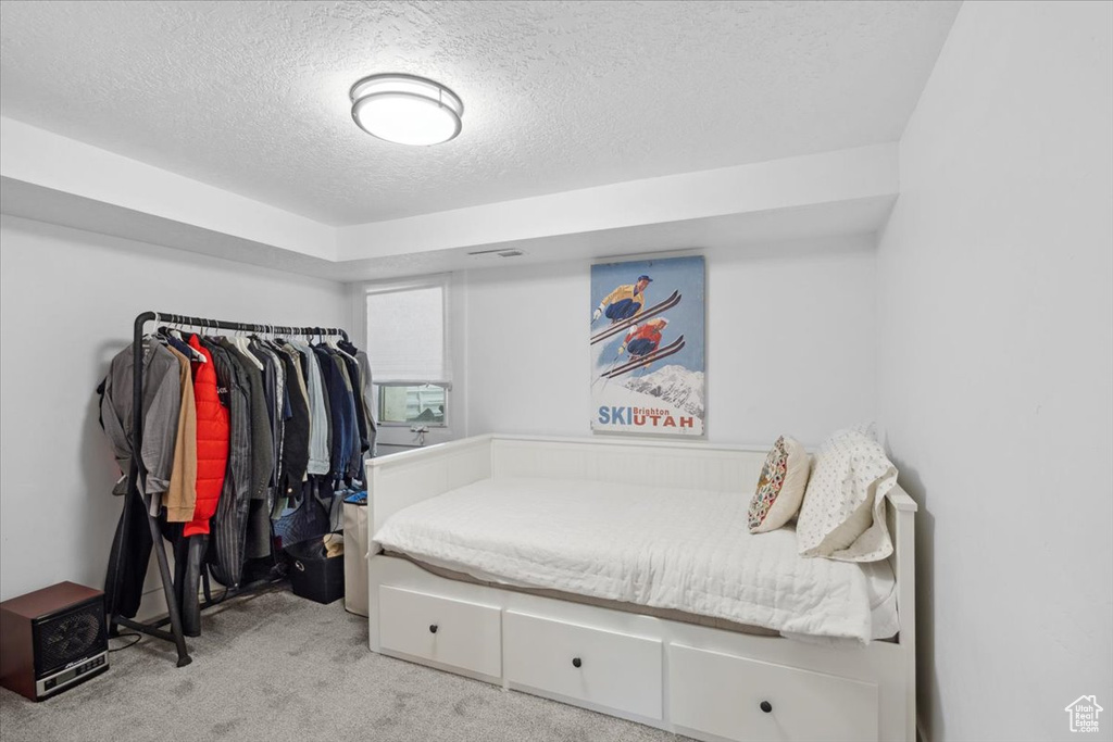 Bedroom featuring light carpet and a textured ceiling