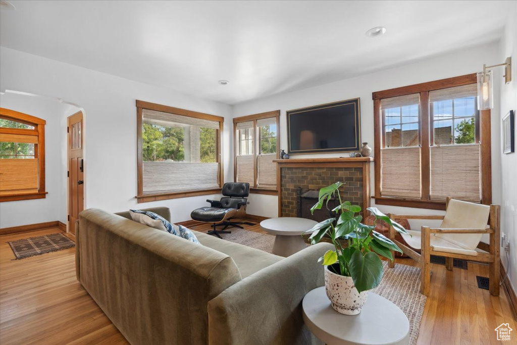 Living room with a brick fireplace, light wood-type flooring, and recessed lighting