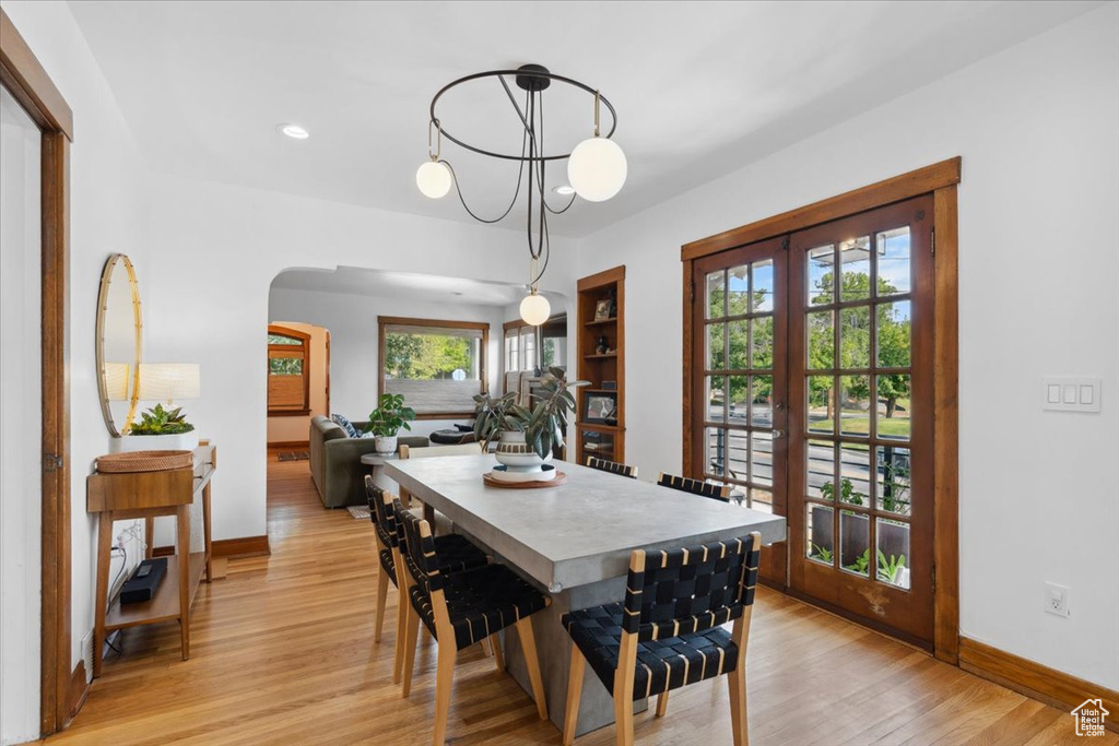 Dining space with arched walkways, light wood finished floors, french doors, and recessed lighting
