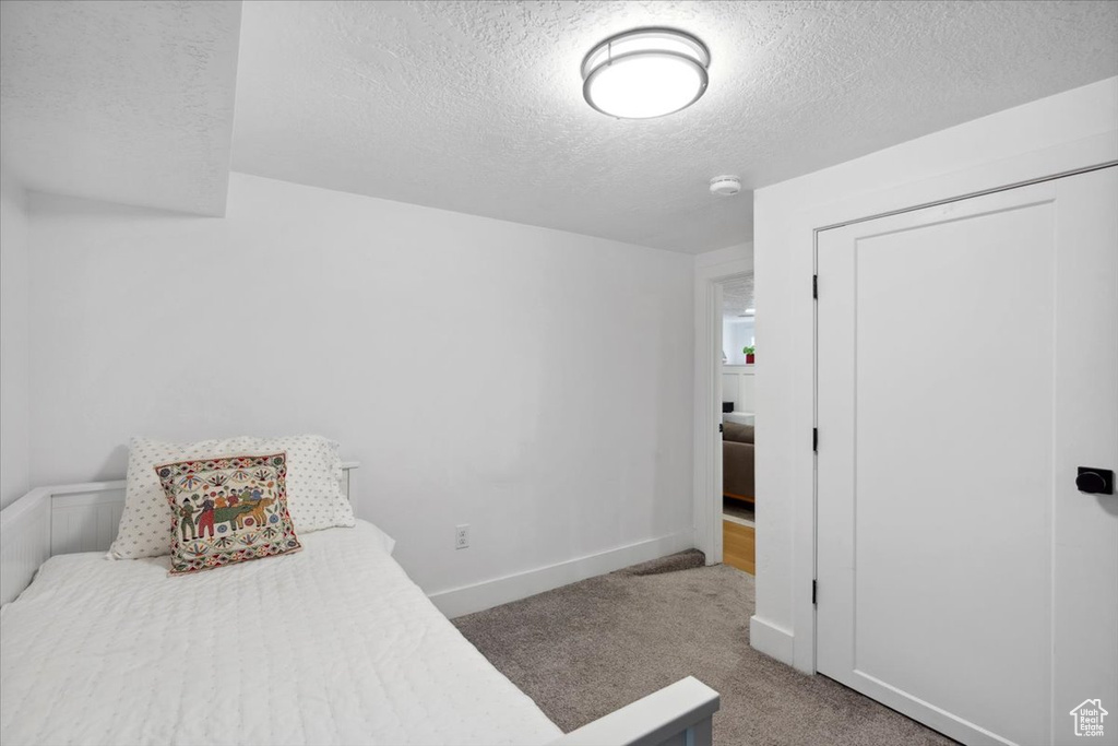 Bedroom featuring a textured ceiling, carpet, and a closet