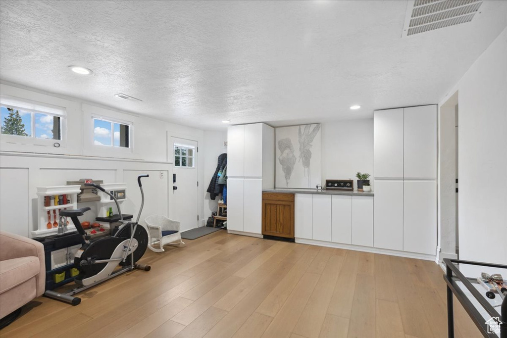 Exercise area featuring light wood finished floors, plenty of natural light, a textured ceiling, and recessed lighting