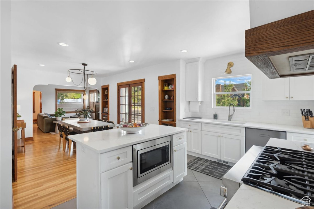 Kitchen with stainless steel appliances, premium range hood, light countertops, backsplash, and recessed lighting