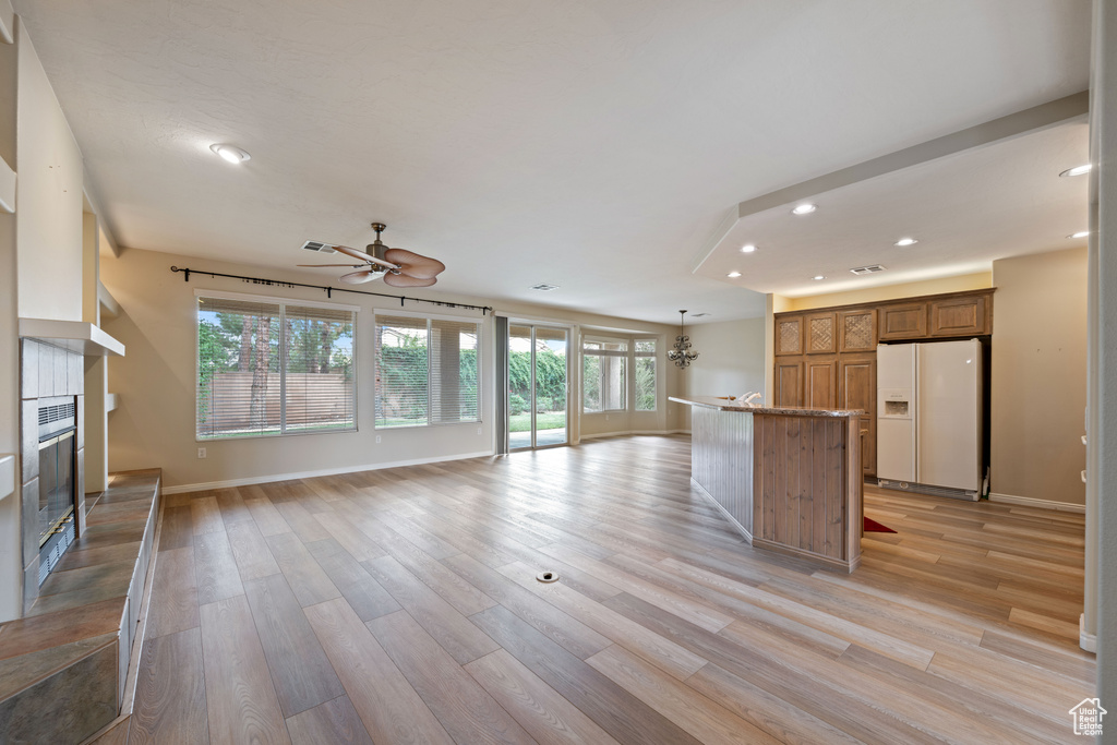 Unfurnished living room featuring recessed lighting, a glass covered fireplace, light wood-style floors, and a ceiling fan