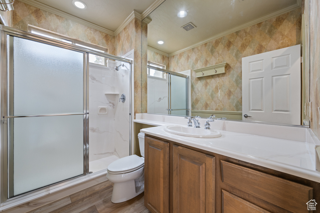 Full bathroom featuring crown molding, vanity, wood finished floors, a shower stall, and wallpapered walls