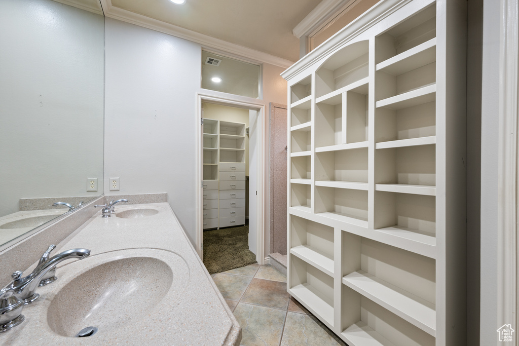 Full bath with double vanity, crown molding, a walk in closet, and tile patterned floors
