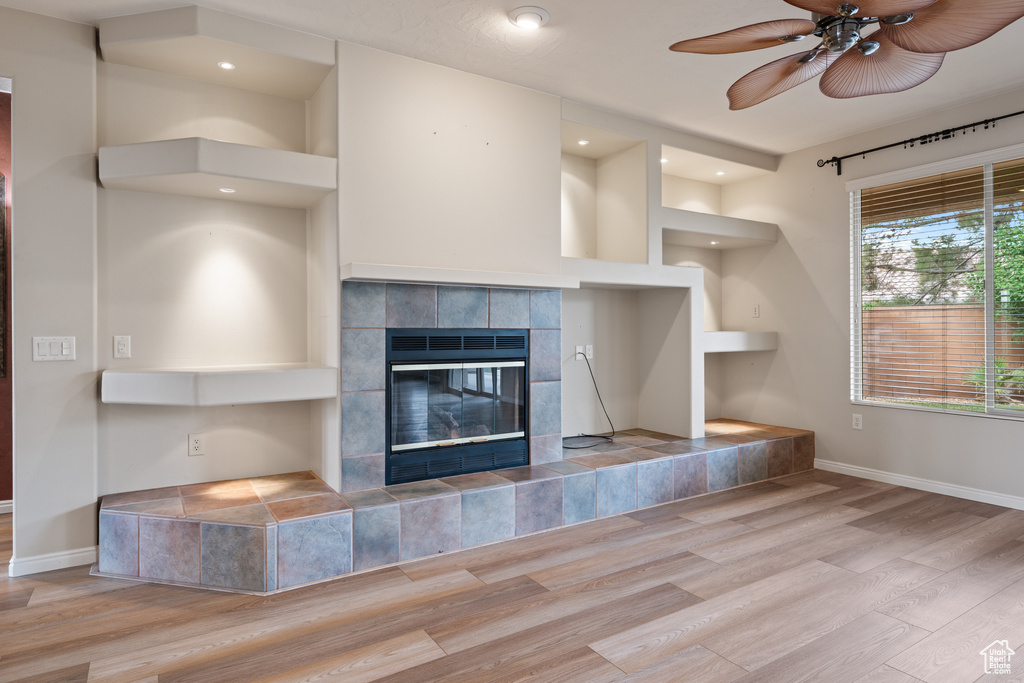 Unfurnished living room featuring wood finished floors, a tiled fireplace, ceiling fan, and recessed lighting