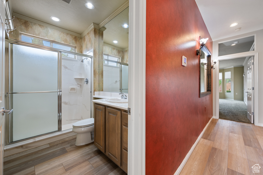 Bathroom featuring wood finished floors, crown molding, a shower stall, vanity, and recessed lighting