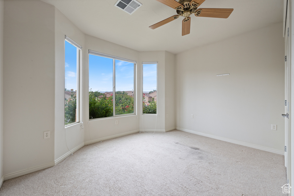 Unfurnished room featuring healthy amount of natural light, carpet floors, and ceiling fan