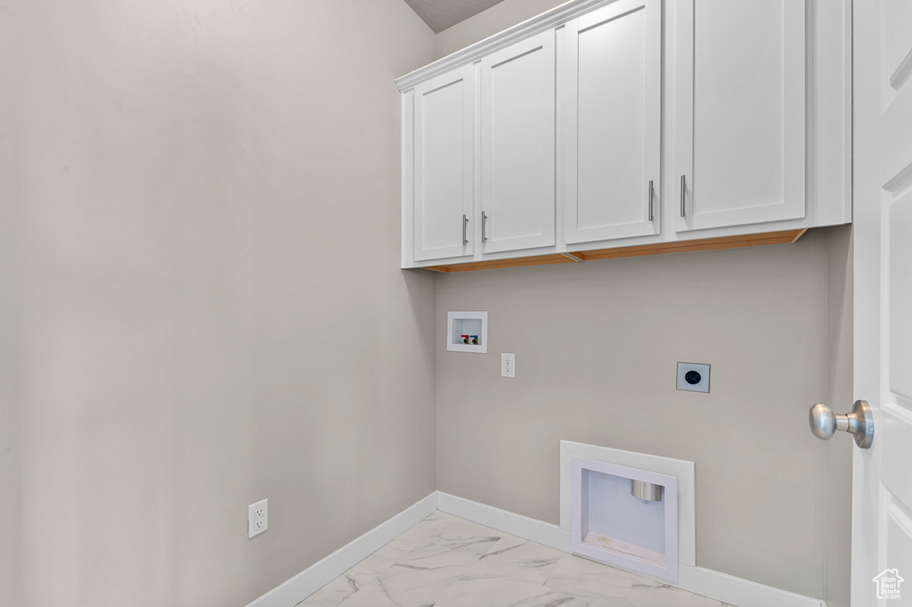 Laundry area featuring cabinet space, electric dryer hookup, hookup for a washing machine, and light marble finish floors
