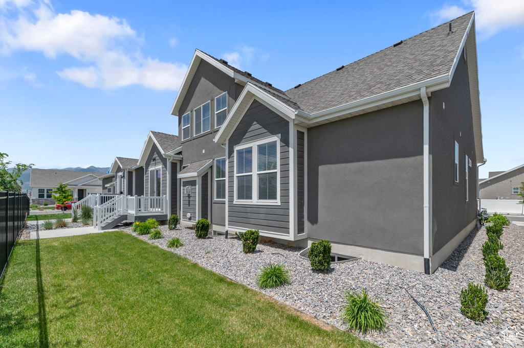 View of side of home featuring a residential view, roof with shingles, a wooden deck, and stucco siding