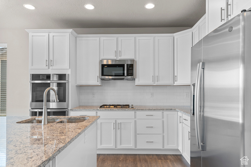 Kitchen featuring stainless steel appliances, white cabinets, dark wood finished floors, recessed lighting, and tasteful backsplash