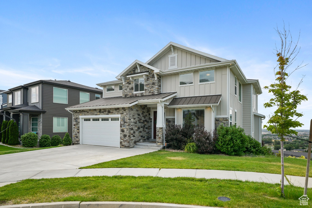 Craftsman-style home featuring driveway, board and batten siding, a front yard, stone siding, and a standing seam roof