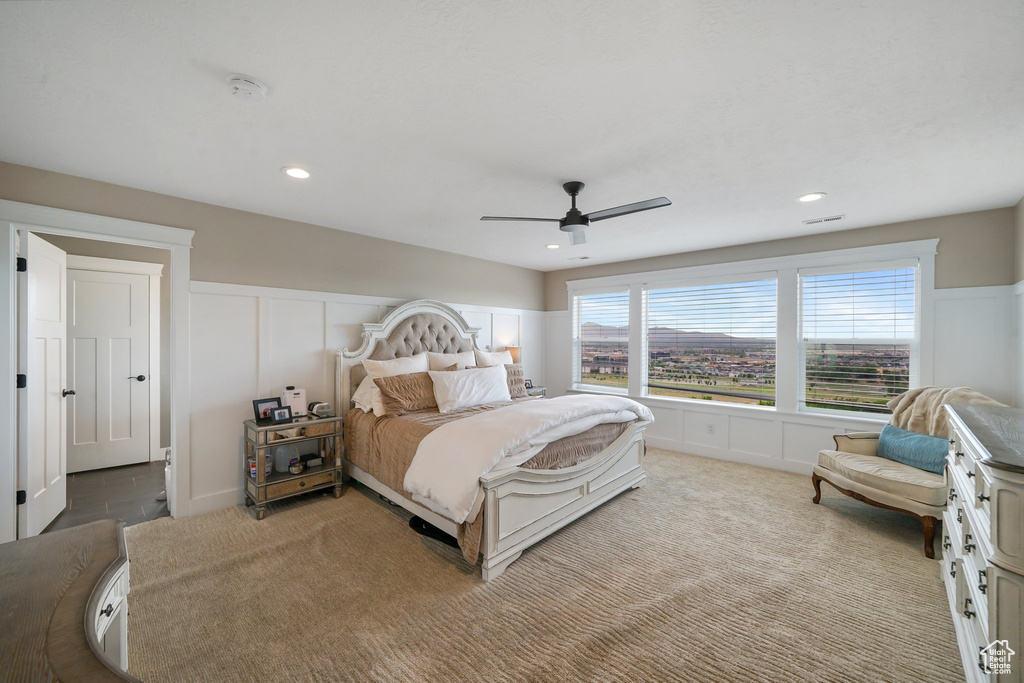 Carpeted bedroom featuring a decorative wall, wainscoting, a ceiling fan, and recessed lighting
