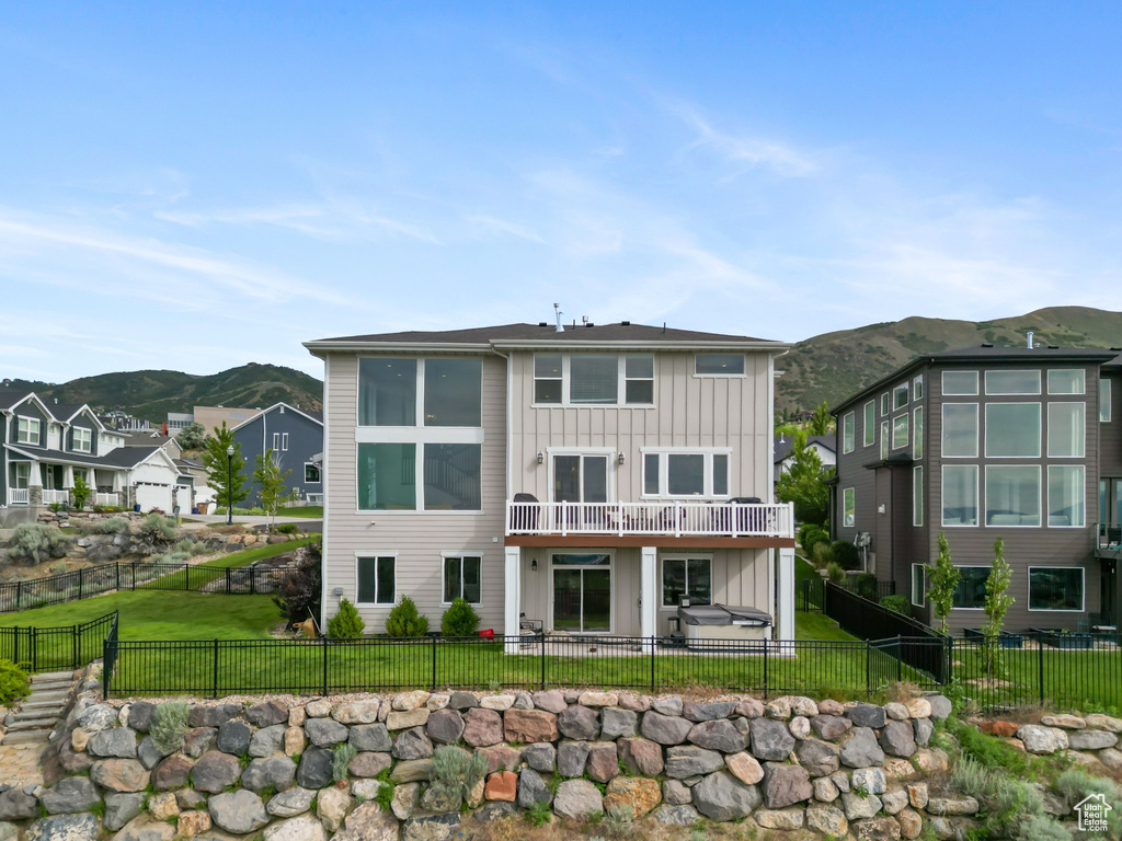 Rear view of property with board and batten siding, a mountain view, a fenced backyard, and a patio area