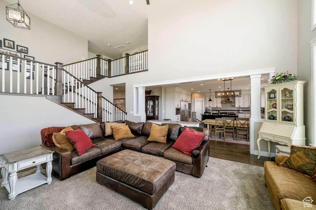 Living area with a towering ceiling, decorative columns, stairs, and wood finished floors