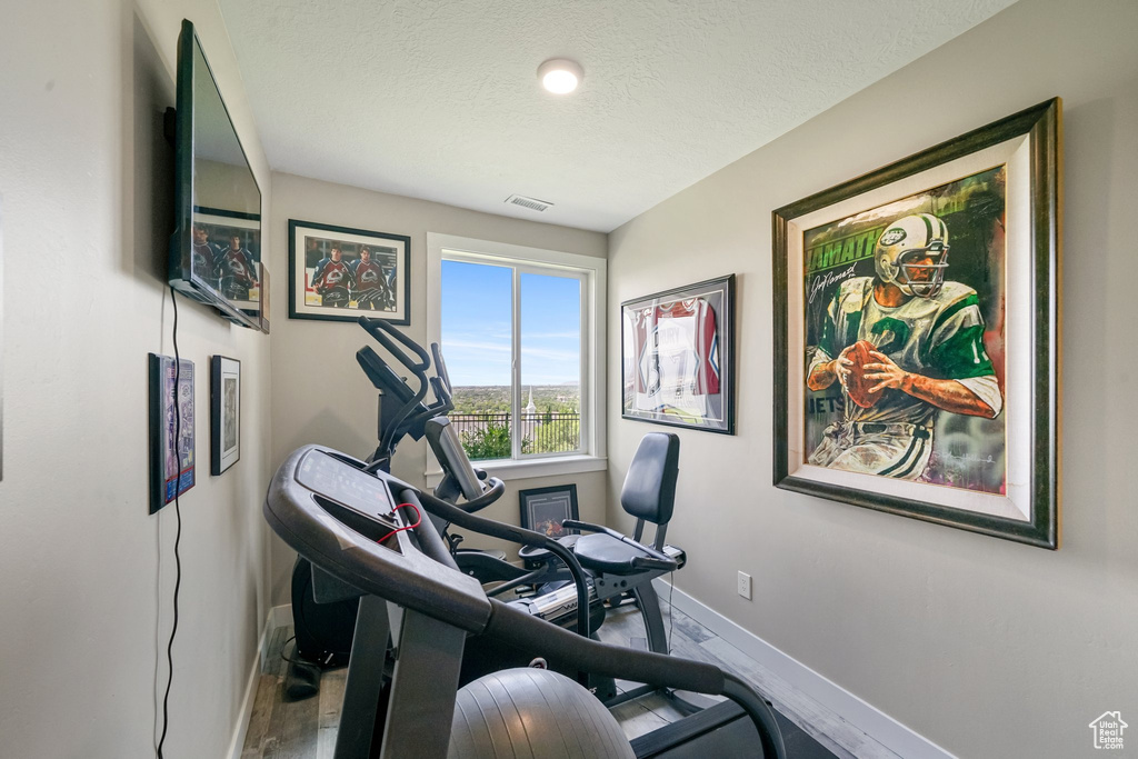 Exercise area with baseboards and a textured ceiling