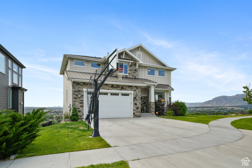 Craftsman house featuring driveway, a garage, a front lawn, board and batten siding, and a mountain view