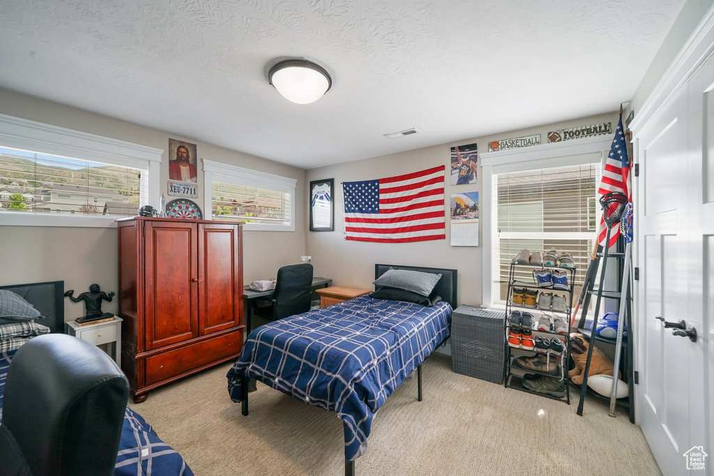 Bedroom featuring light colored carpet and a textured ceiling