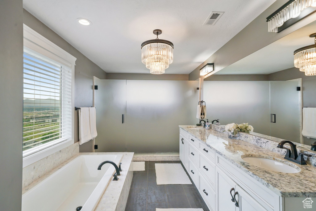 Bathroom with a chandelier, double vanity, a garden tub, and wood finished floors