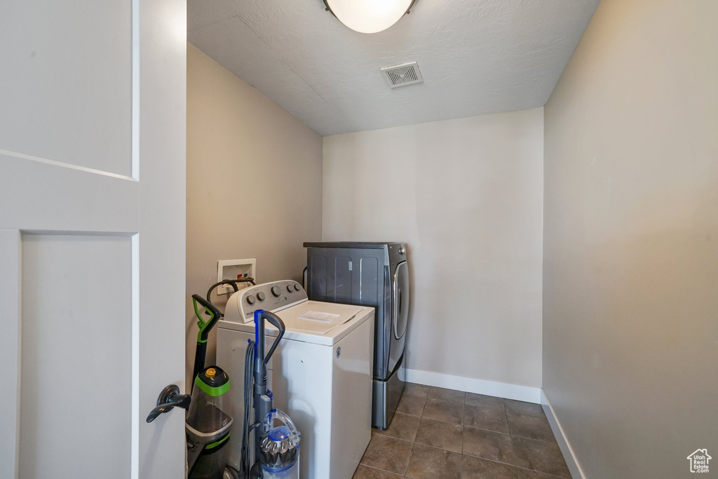 Washroom featuring washer and dryer and dark tile patterned floors