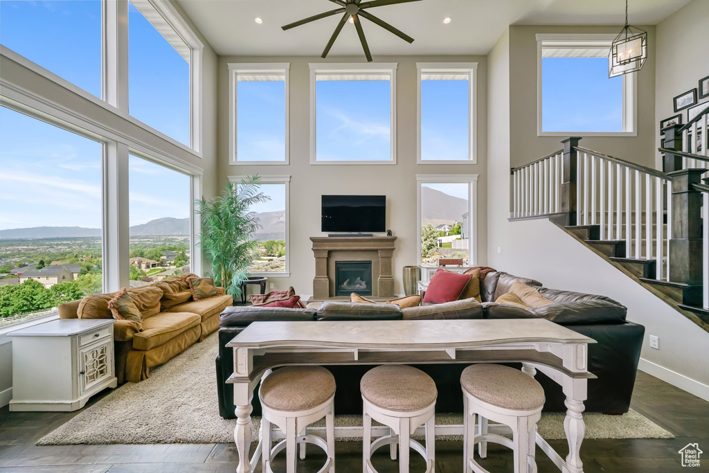 Living room featuring a high ceiling, stairs, a glass covered fireplace, dark wood-style flooring, and recessed lighting