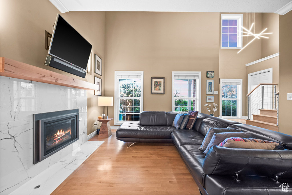 Living room featuring wood finished floors, a tile fireplace, stairs, and a towering ceiling