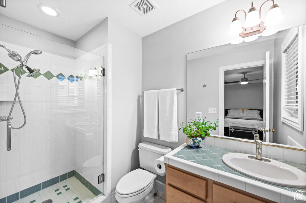 Full bath featuring a stall shower, ensuite bathroom, vanity, and a ceiling fan