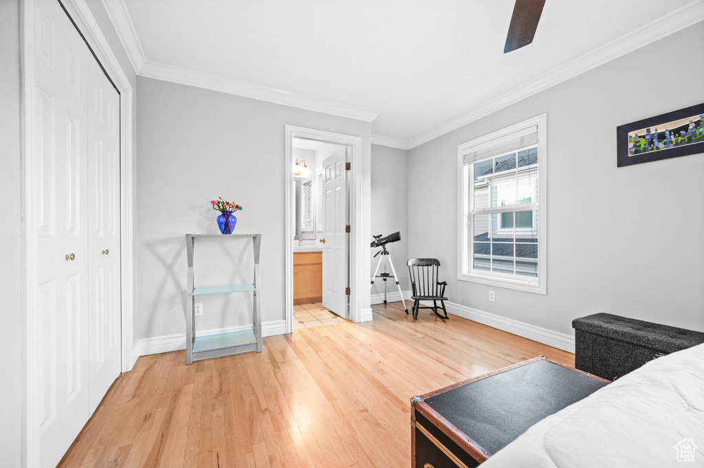 Bedroom with ornamental molding, light wood-style flooring, a closet, connected bathroom, and a ceiling fan