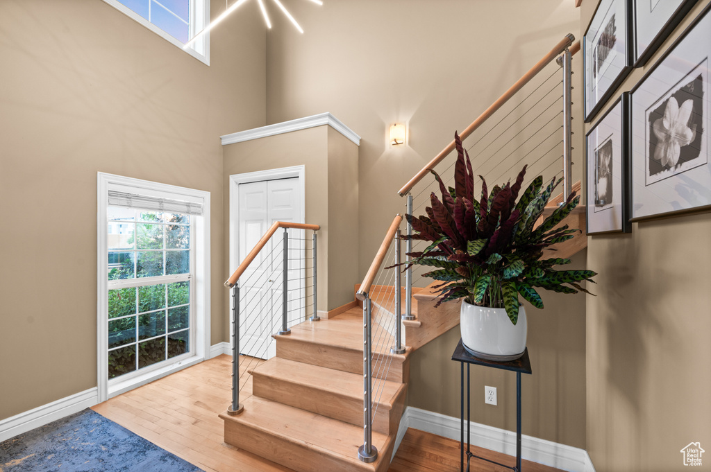 Entrance foyer with wood finished floors, stairs, and a high ceiling
