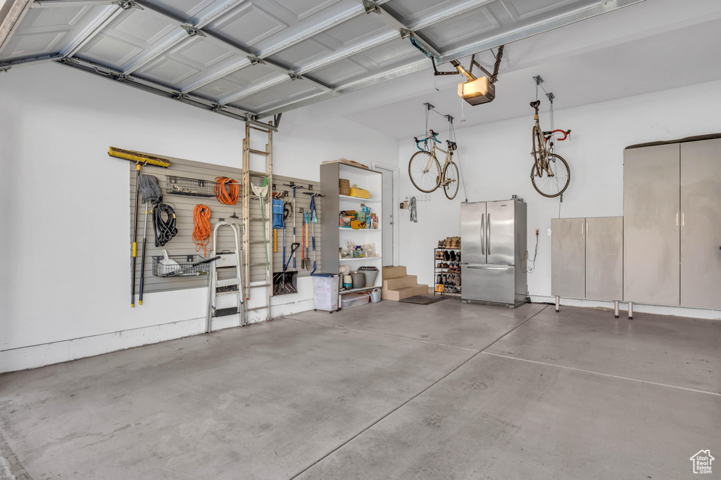 Garage featuring freestanding refrigerator and a garage door opener