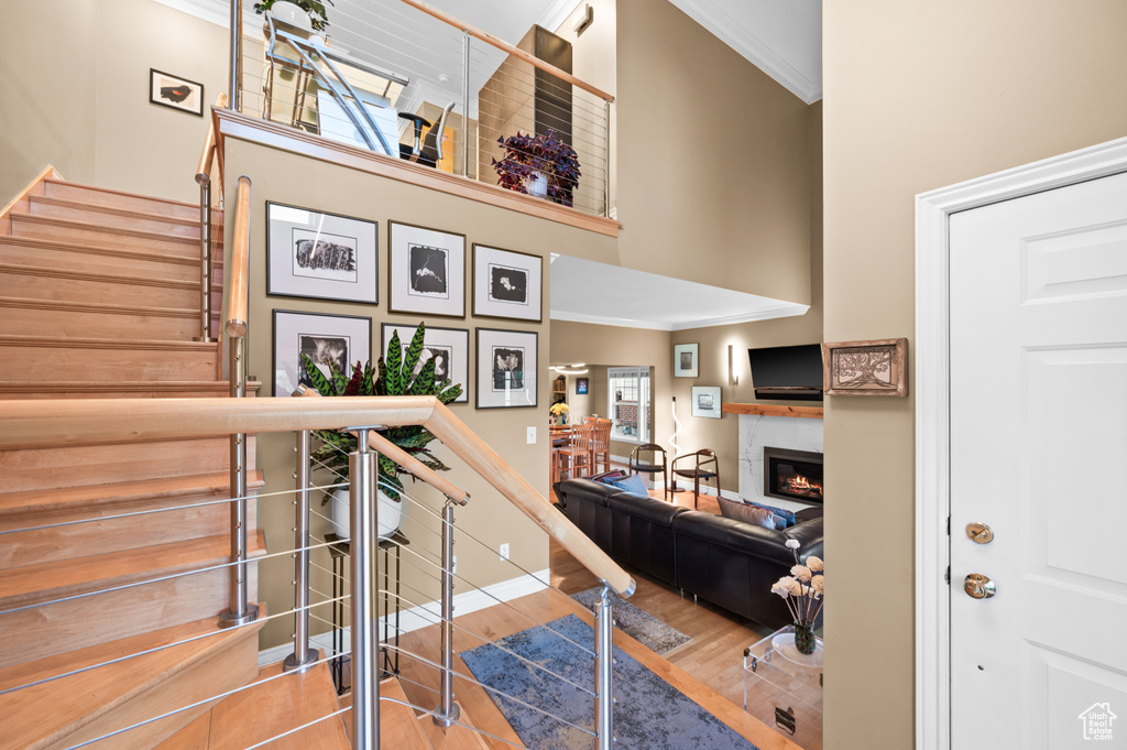 Stairs featuring ornamental molding, a high ceiling, a high end fireplace, and wood finished floors
