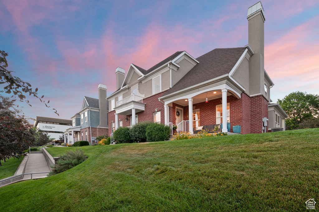 View of front of home featuring brick siding, a chimney, a front lawn, and a porch
