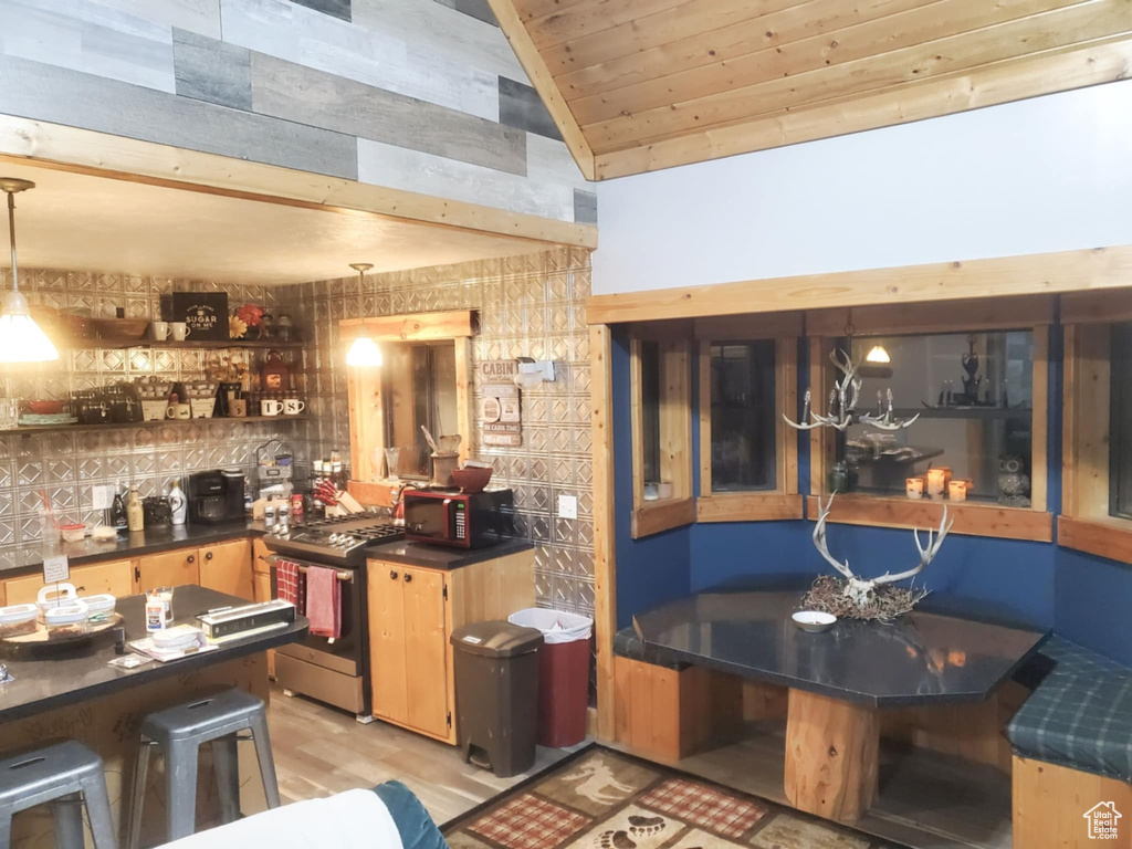 Bar with stainless steel range with gas cooktop, lofted ceiling, light wood-style flooring, black microwave, and wood ceiling