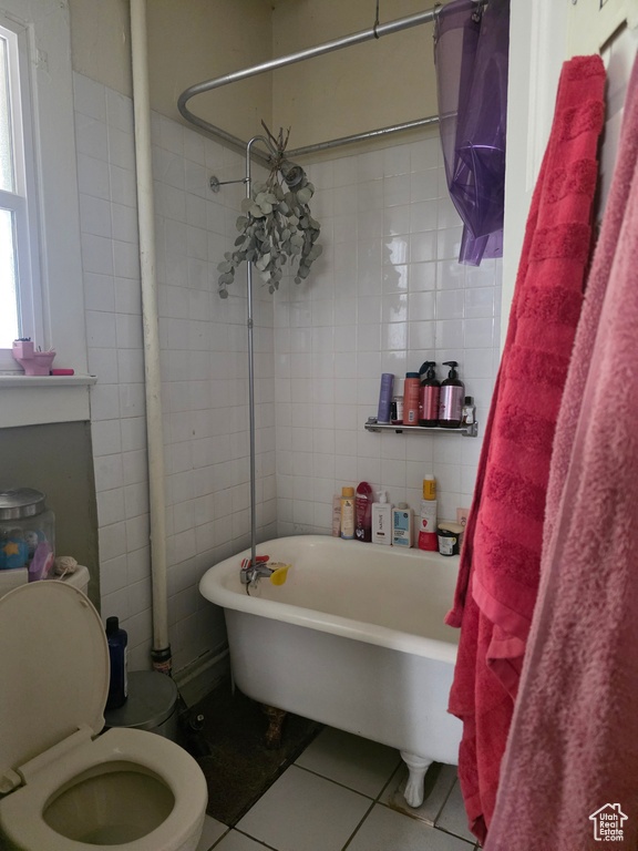 Bathroom featuring tile patterned flooring, a bathtub, toilet, a shower with curtain, and tile walls
