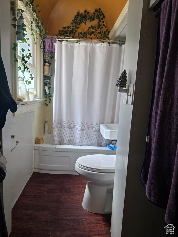 Full bathroom featuring wood finished floors, toilet, shower / bath combo with shower curtain, and lofted ceiling
