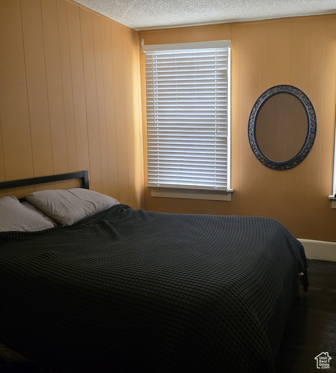 Bedroom with wood finished floors, baseboards, and a decorative wall