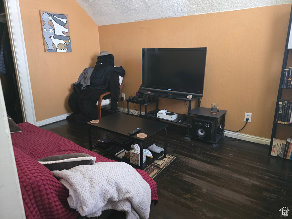Living room with wood finished floors, lofted ceiling, and baseboards