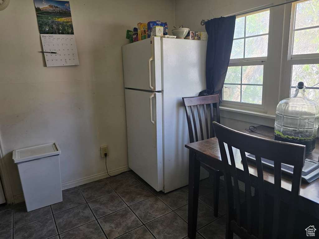 Kitchen with freestanding refrigerator, dark tile patterned floors, and baseboards