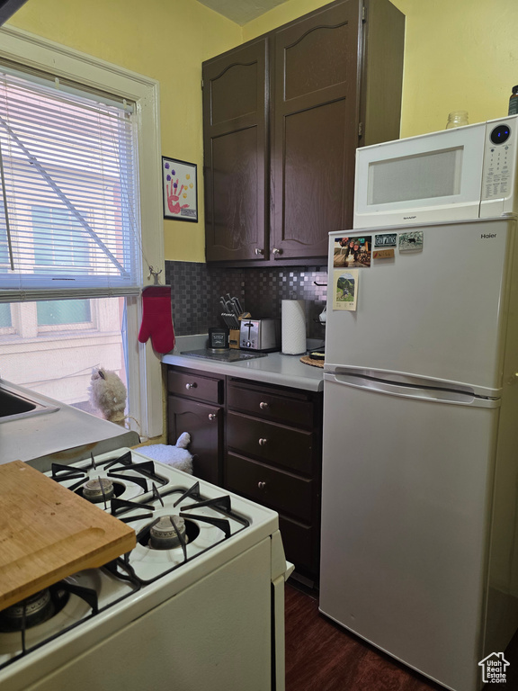 Kitchen featuring white appliances, dark wood finished floors, light countertops, and dark brown cabinets