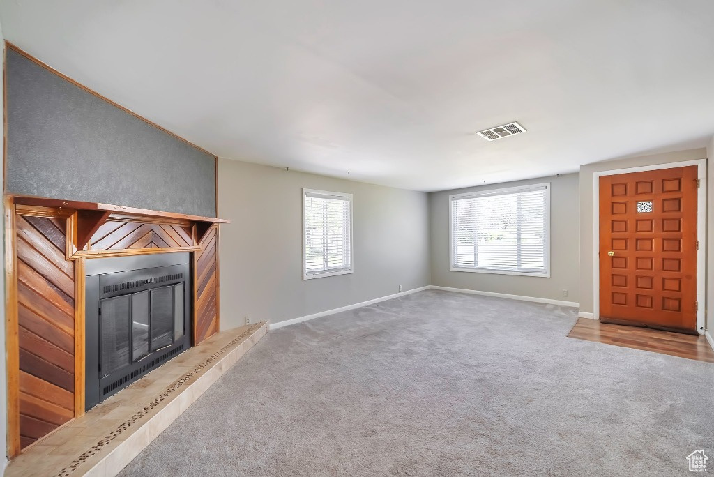 Unfurnished living room with a glass covered fireplace and carpet floors